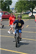 Residents Watch as Child Rides Bike