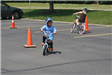 Young Children Ride Bikes Through Course
