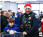An officer and a child are pushing a shopping cart together