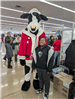 A child stands next to a cow mascot that is wearing a santa suit