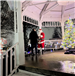 A man is seen standing on the Gazebo stage with Santa Claus and a Christmas Tree