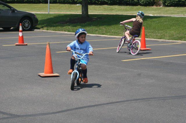 Young Children Ride Bikes Through Course