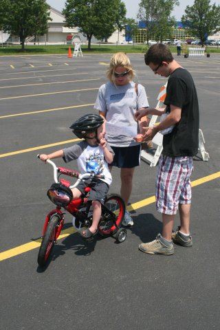 Young People Stand with Child on Red Bike