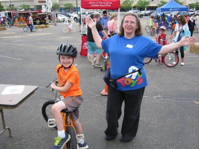 Toys R Us Employee Smiles with Child on Bike