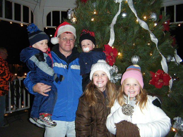 Father Holds Children and Smiles Near Tree