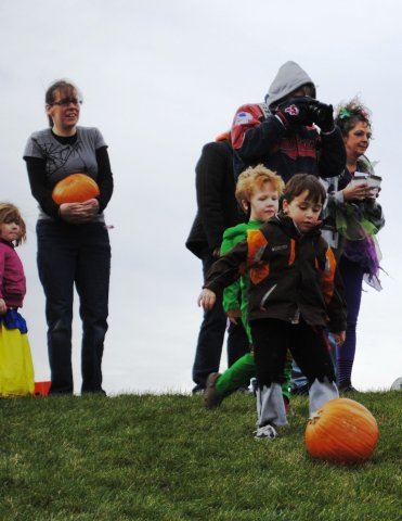 Young People Rolls Pumpkin Down Hill
