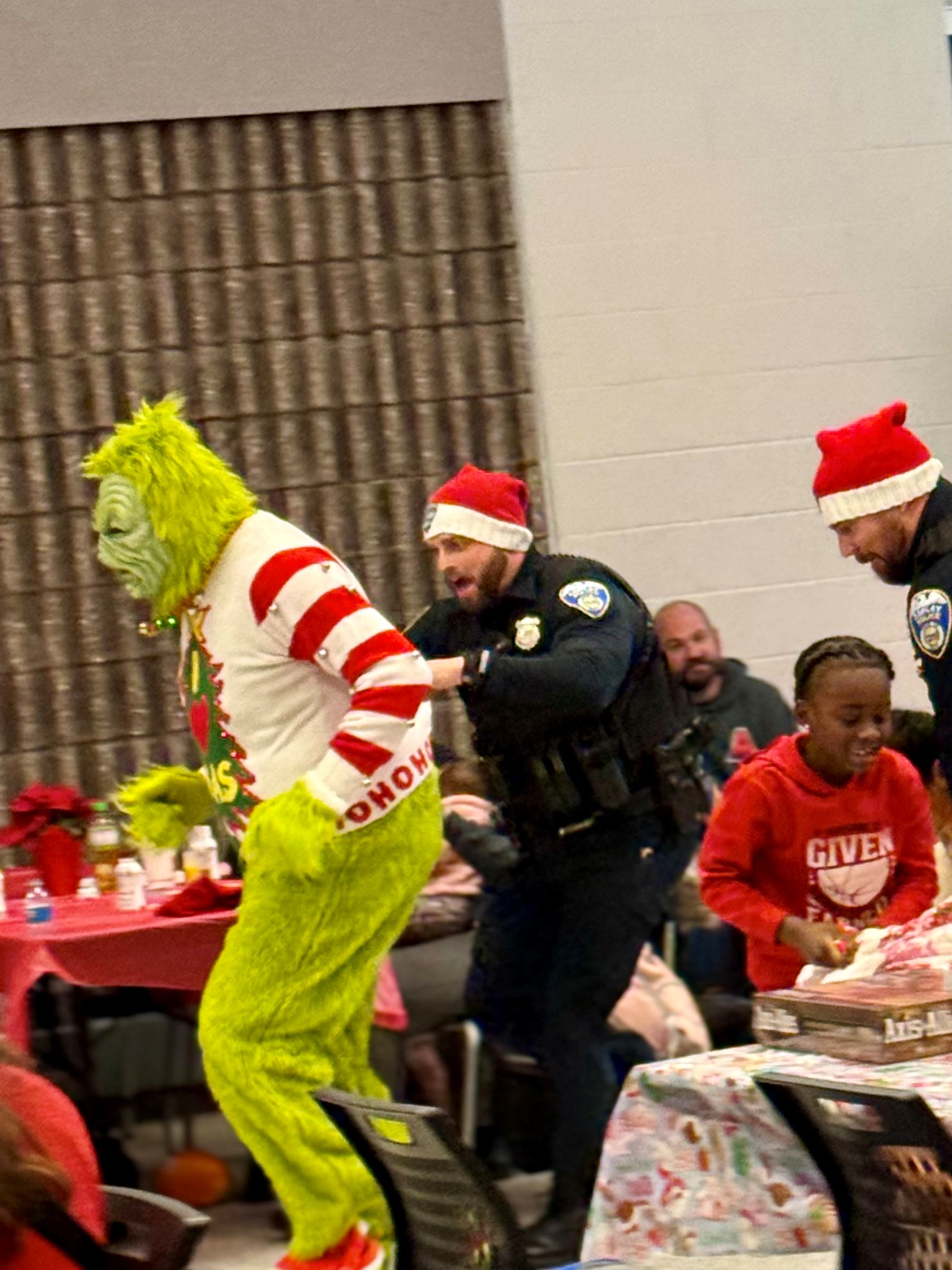 An officer grabs the grinch as he is running away