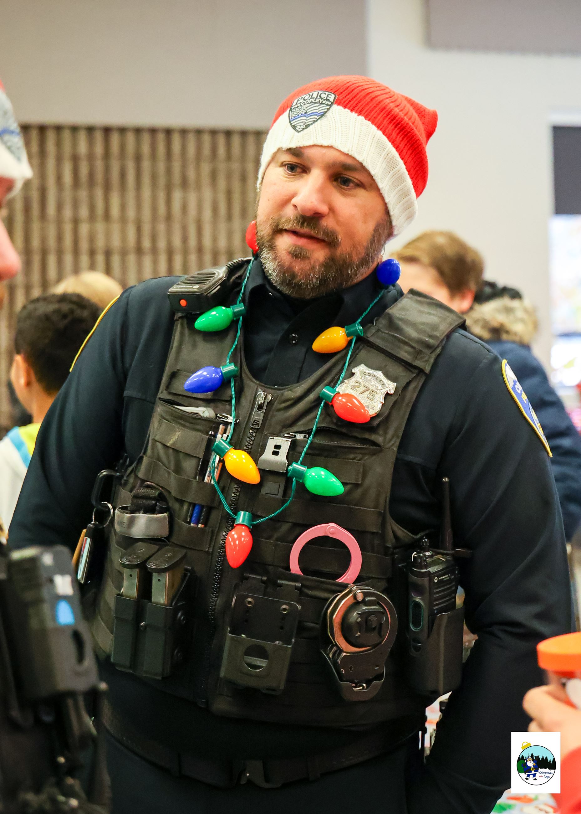 An officer is pictured wearing his utility vest, around his neck is a christmas light necklace