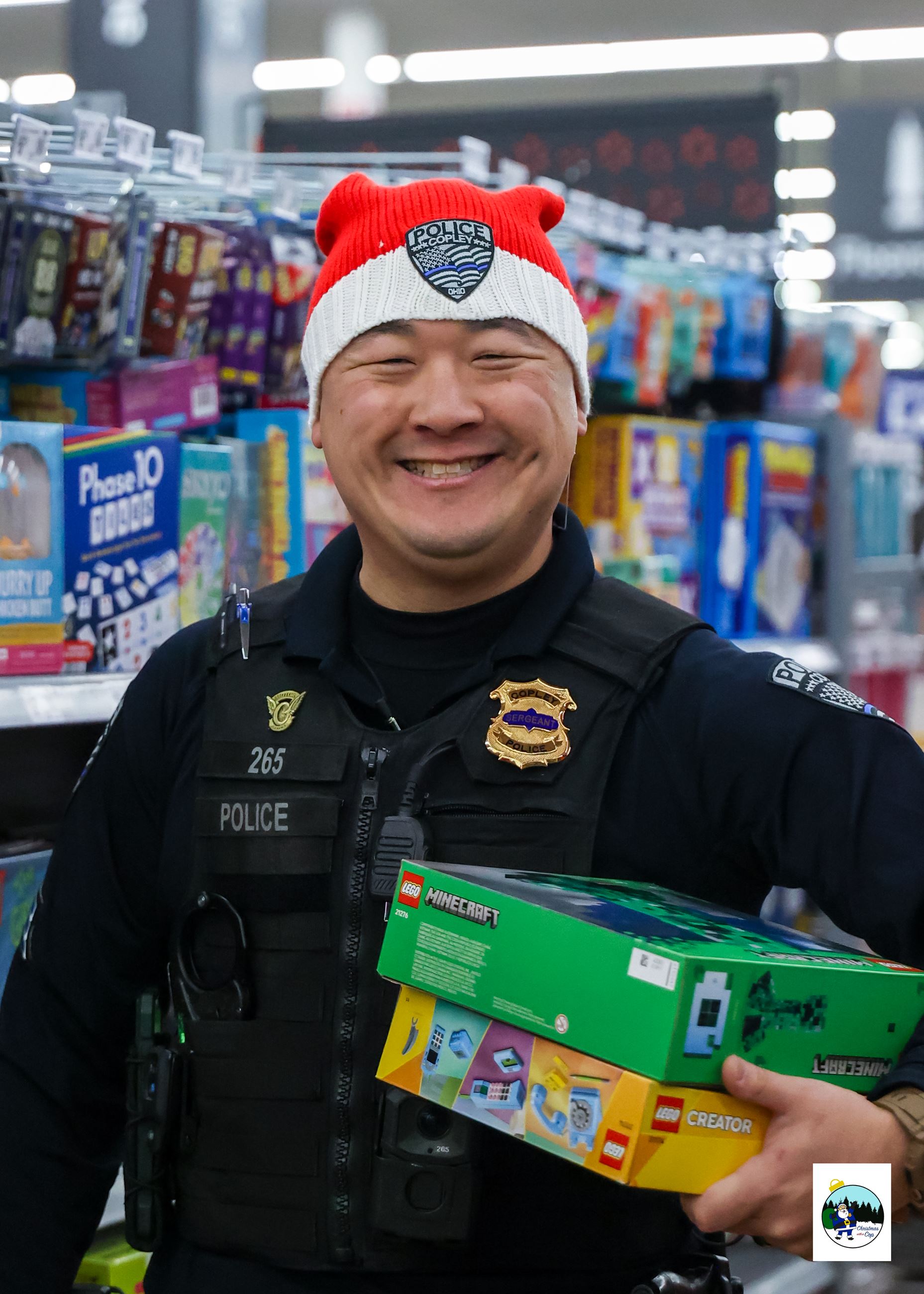 An officer is shown smiling holding gifts under his arm