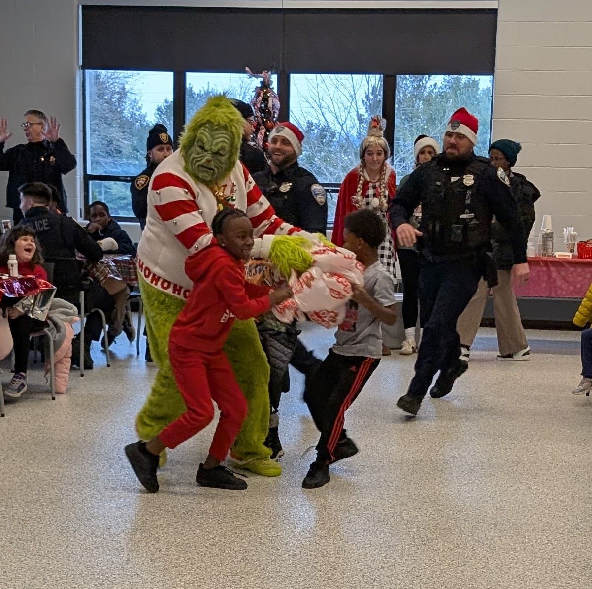 2 Children are seen trying to take a bag of toys from the grinch, in the back 2 cops are running 
