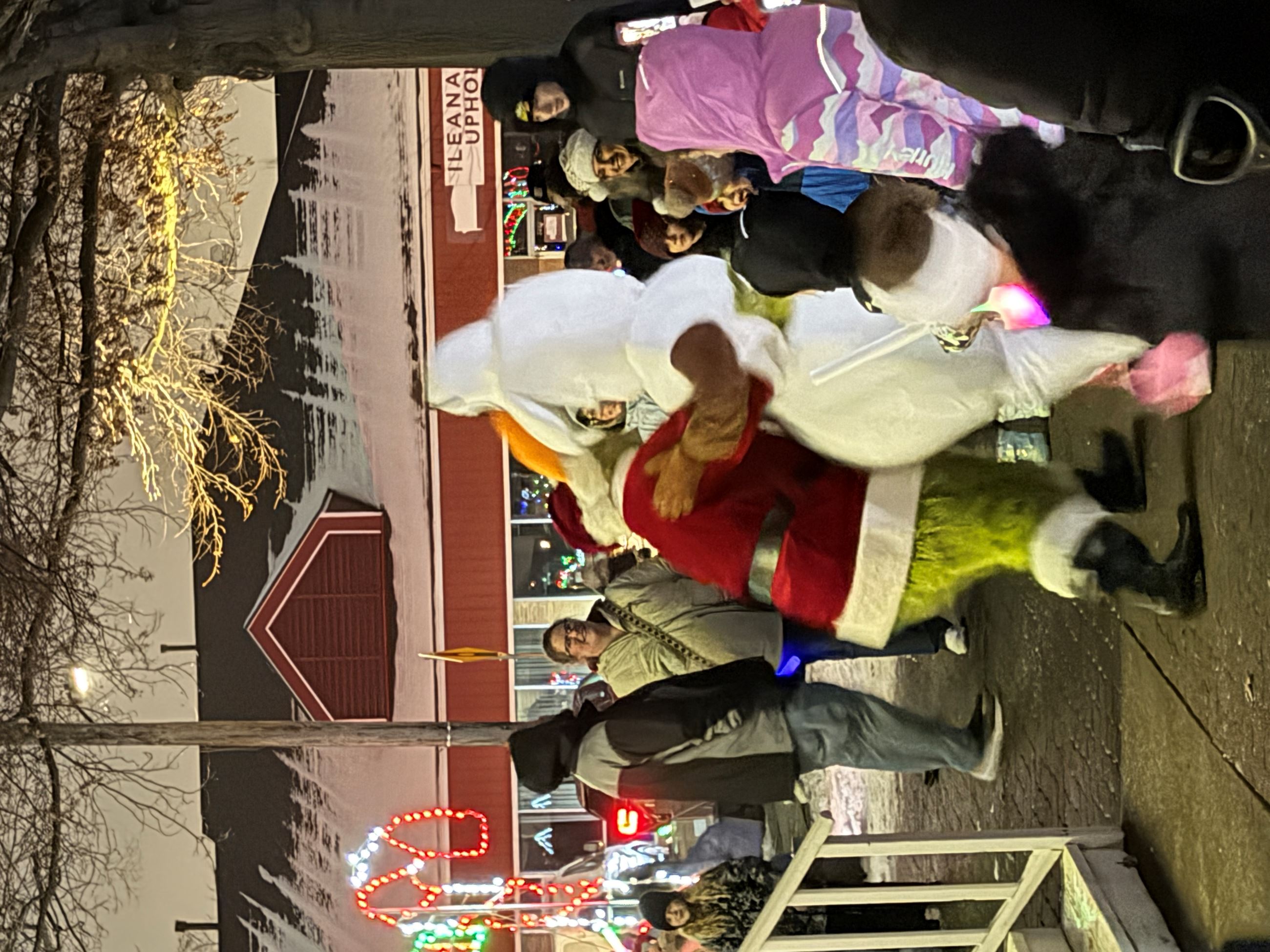 A group of people watch while The Grinch and Olaf dance together hand in hand